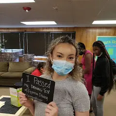 A woman holding up a sign that says " i passed my nursing test ".